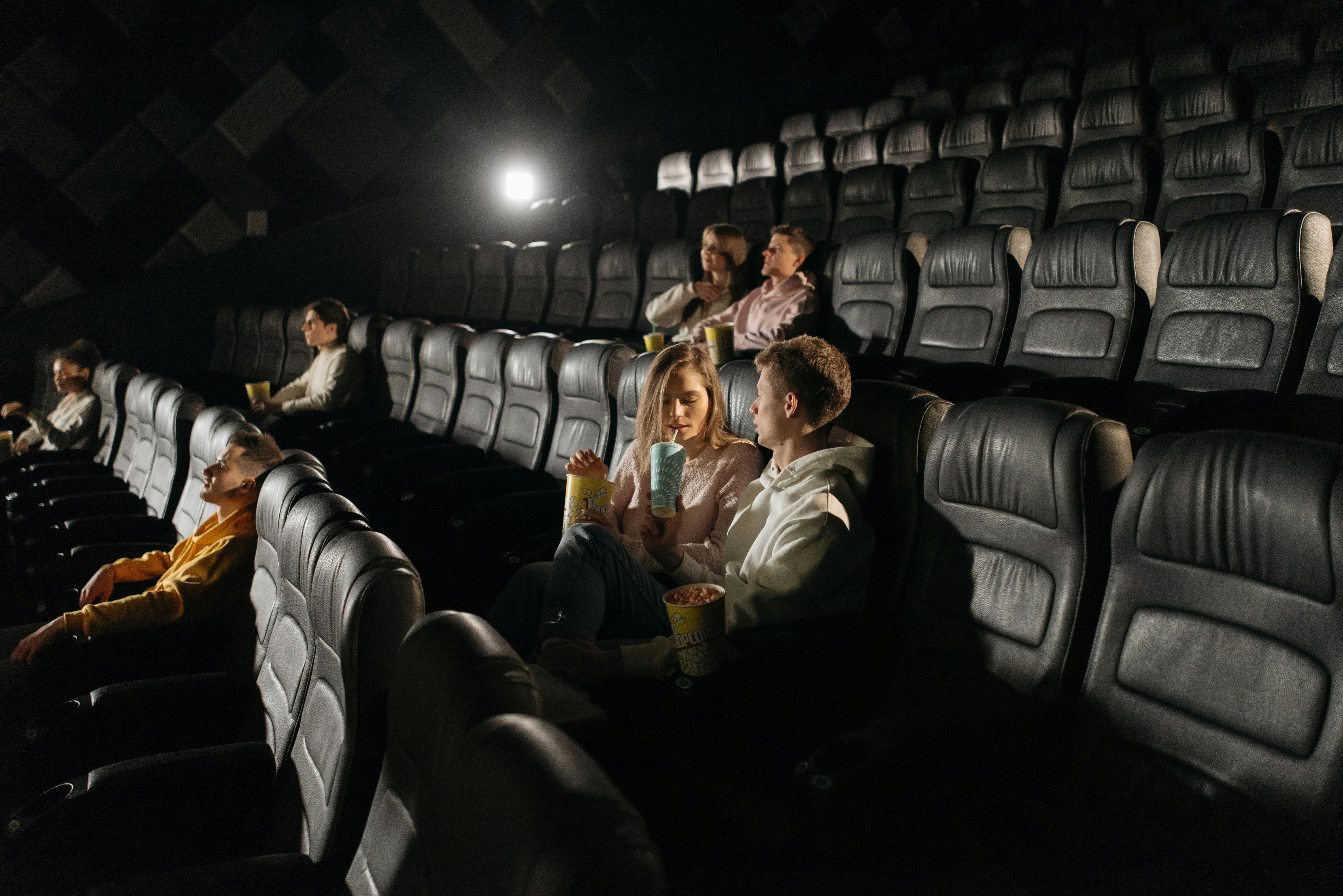 Pareja joven y público en una sala de cine moderna, símbolo del regreso a las salas en 2025