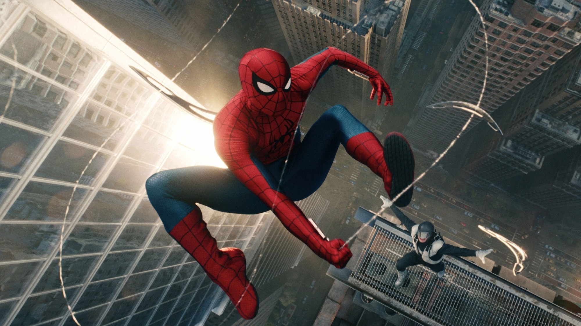 Spider-Man se lanza al vacío entre rascacielos mientras una figura con traje oscuro lo observa desde una cornisa