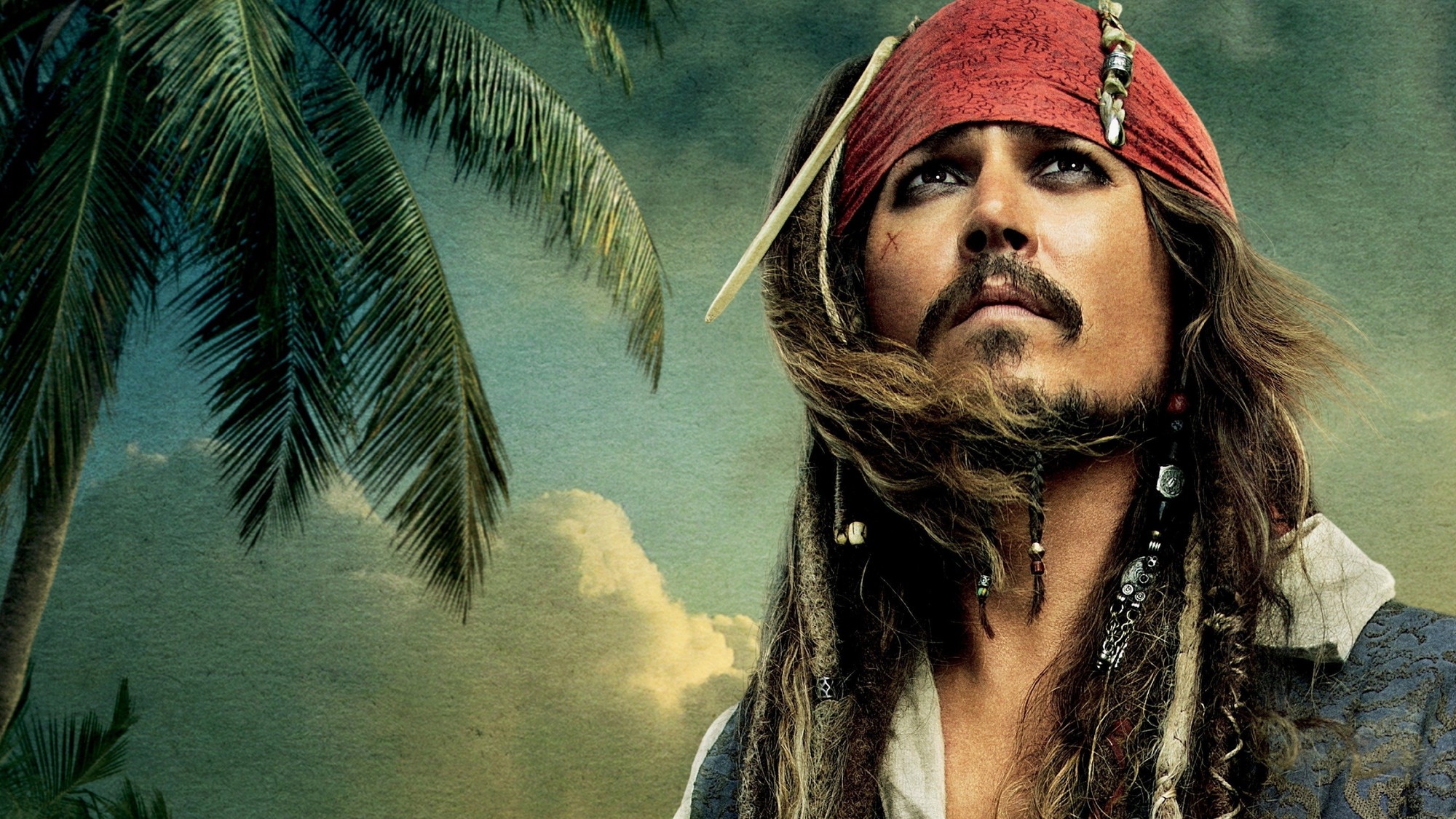 Primer plano de Johnny Depp caracterizado como Jack Sparrow mirando hacia el cielo, con palmeras y nubes al fondo