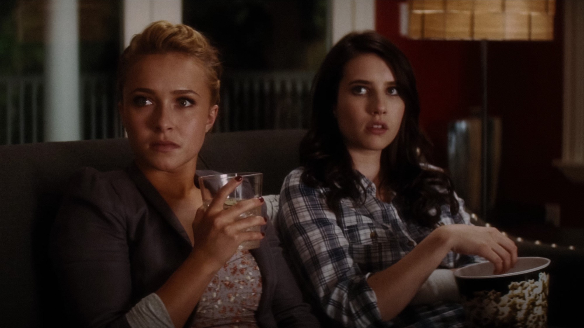 Hayden Panettiere sostiene un vaso sentada en un sillón junto a Emma Roberts en una escena nocturna de Scream 4