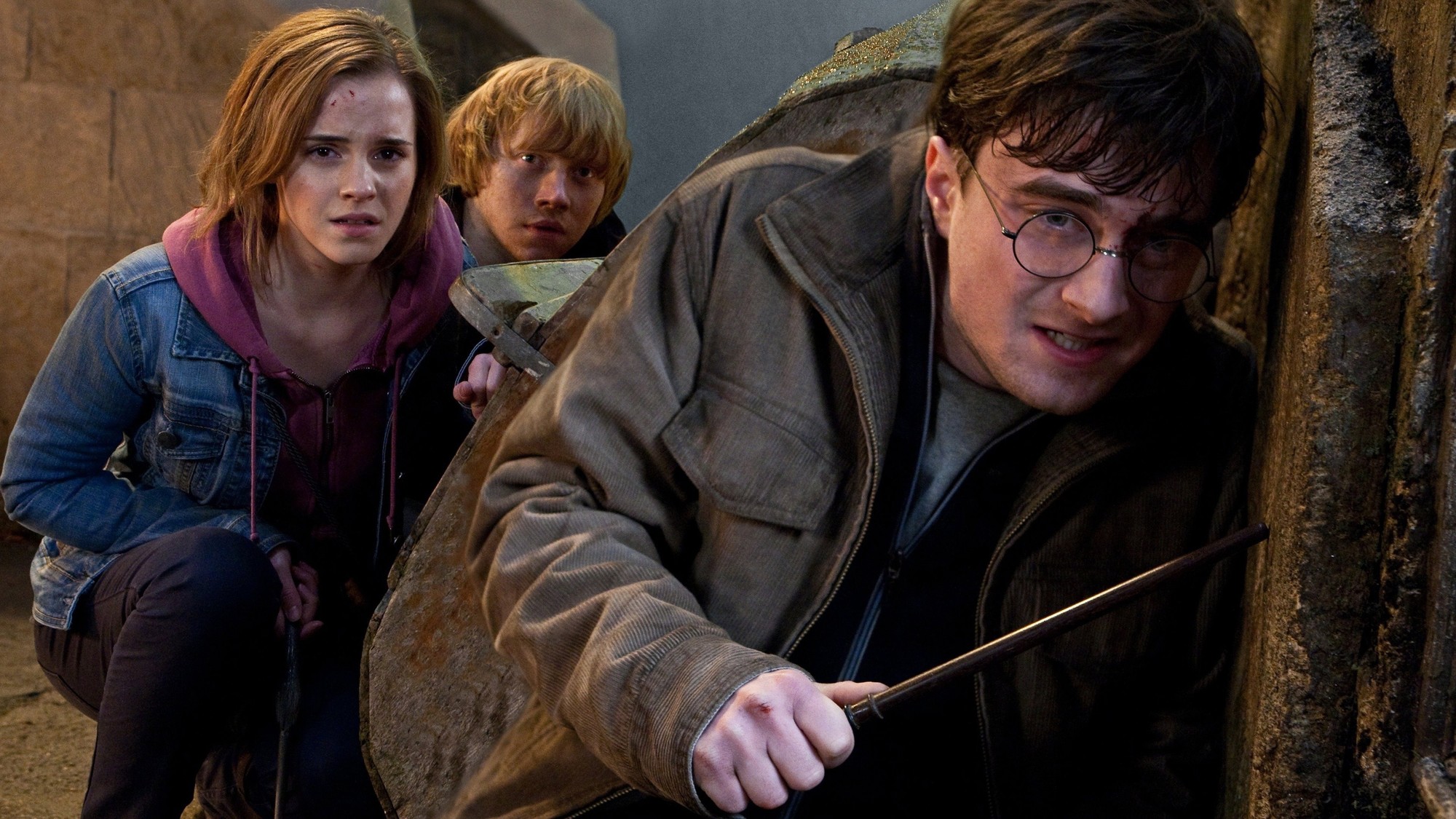 Hermione, Ron y Harry agazapados detrás de una pared durante la batalla de Hogwarts