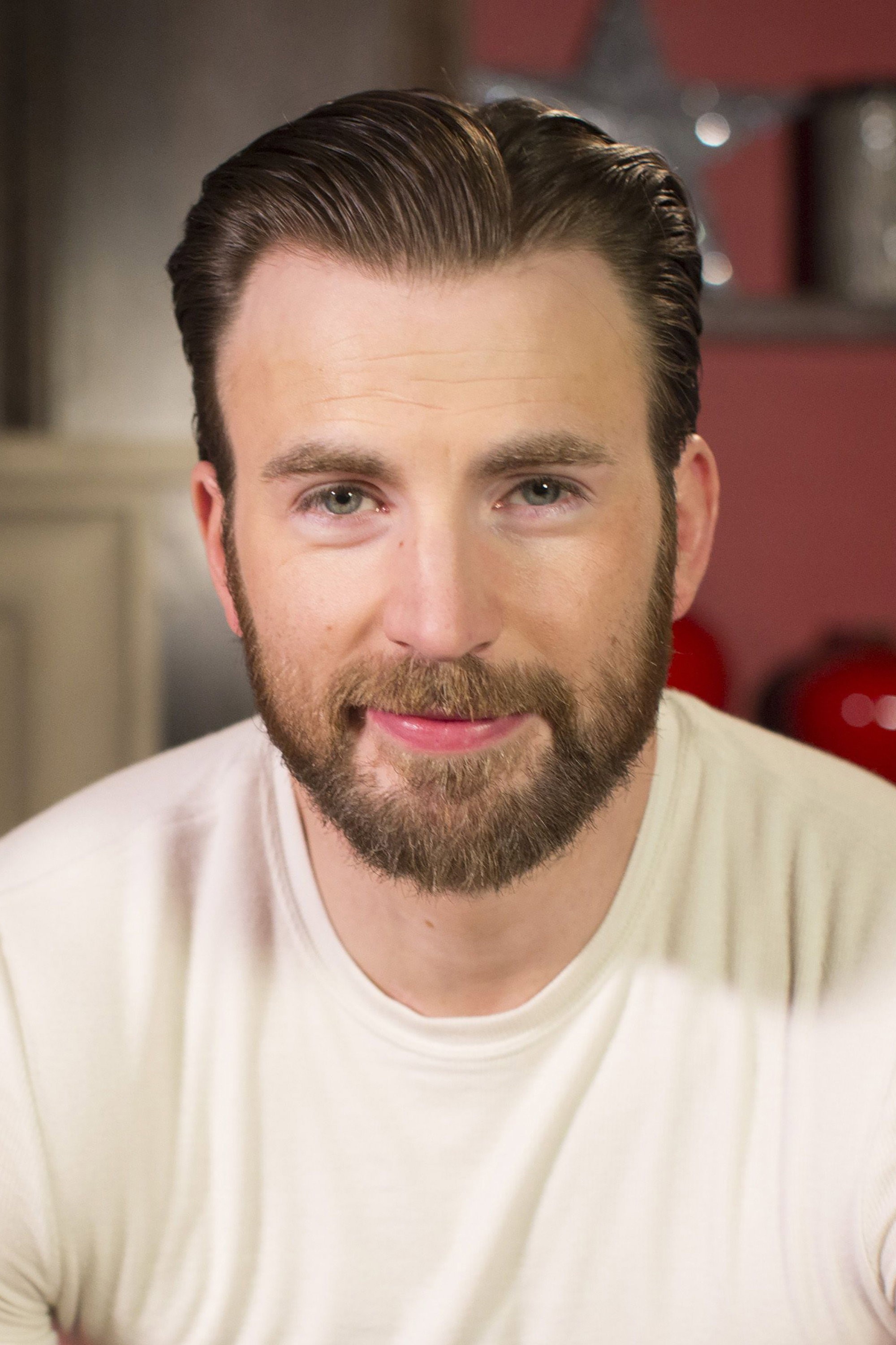 Retrato de Chris Evans con barba y camiseta clara, mirando a cámara con expresión relajada