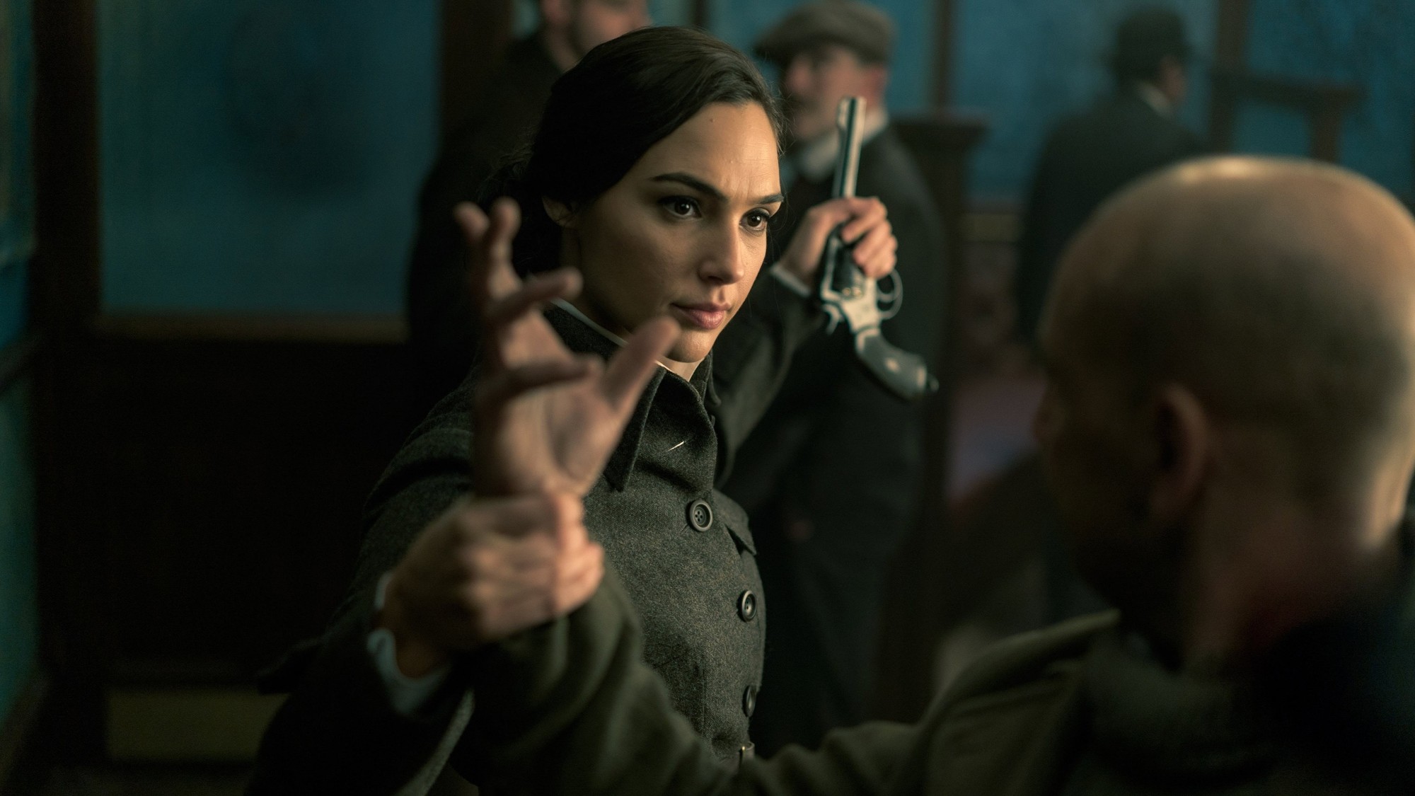 Diana Prince, interpretada por Gal Gadot, vestida de civil y con abrigo de época en un interior en penumbra