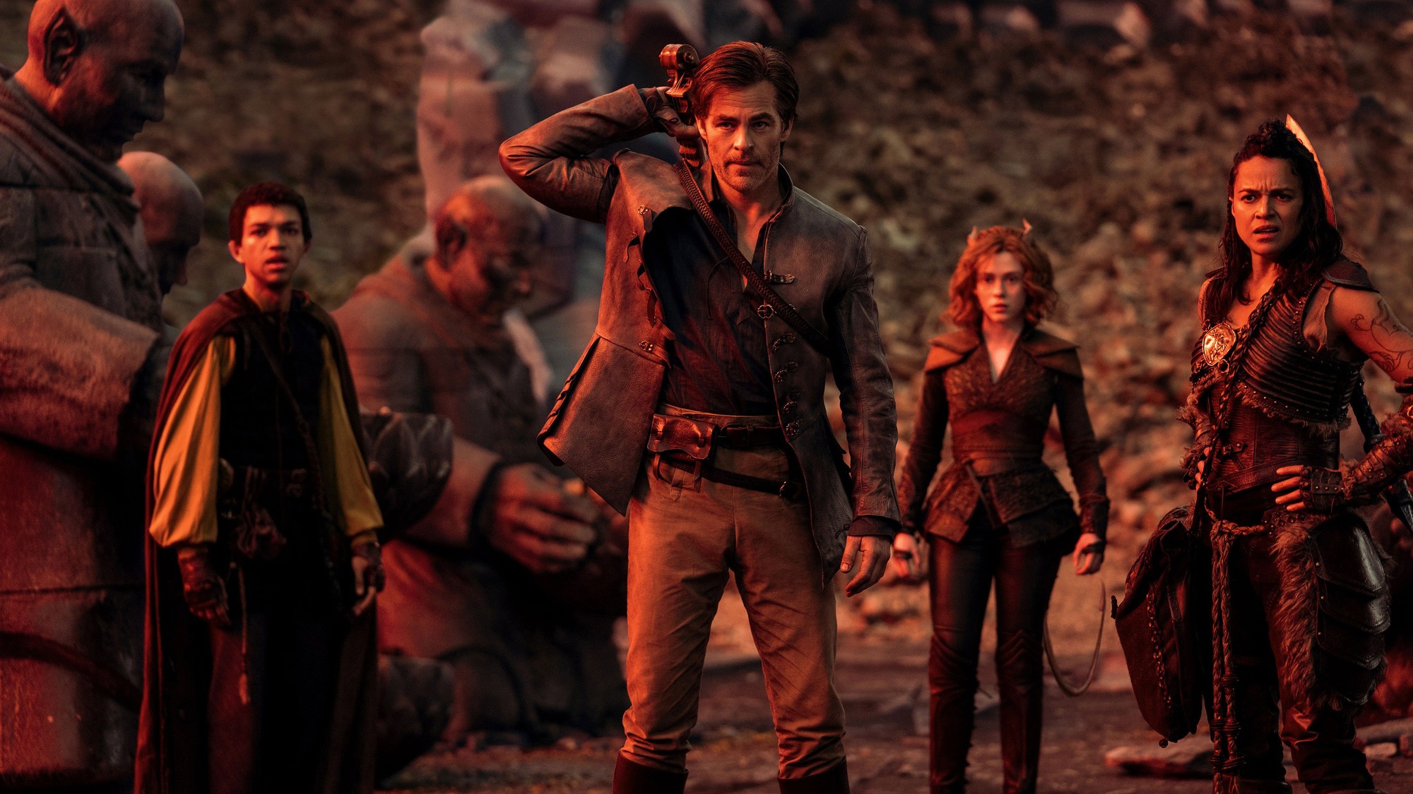 Grupo de aventureros de pie sobre un terreno rocoso bajo una luz rojiza en la película Dungeons & Dragons: Honor entre ladrones