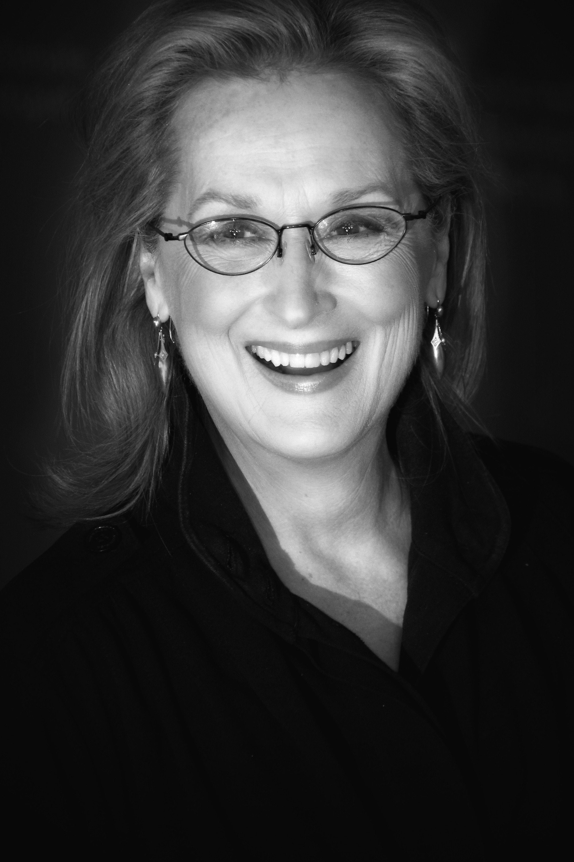 Retrato en blanco y negro de la actriz Meryl Streep sonriendo con lentes de armazón delgado