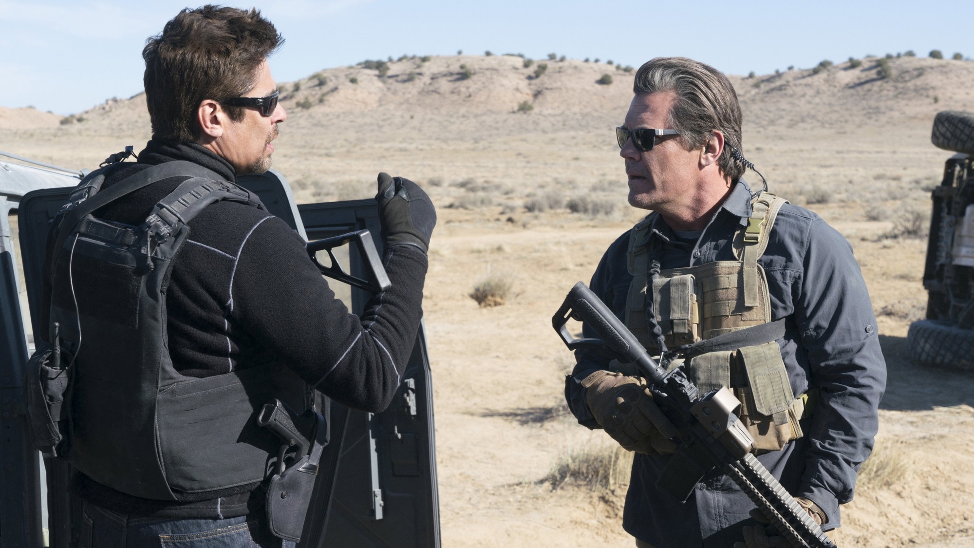 Benicio del Toro y Josh Brolin, armados y con lentes oscuros, conversan en pleno desierto fronterizo durante una operación encubierta