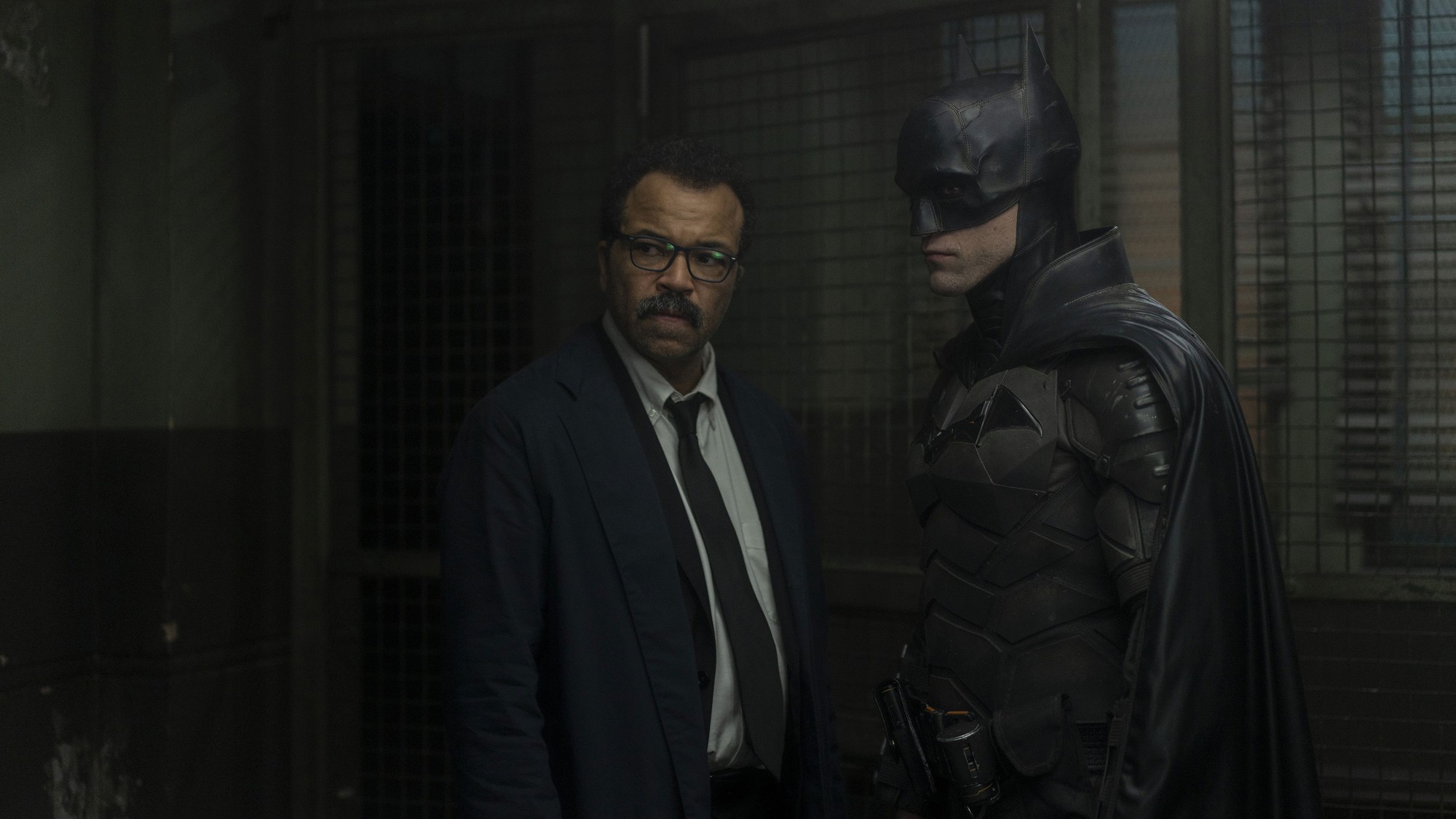 Jeffrey Wright como el teniente James Gordon junto a Batman, interpretado por Robert Pattinson, en un pasillo enrejado en penumbra