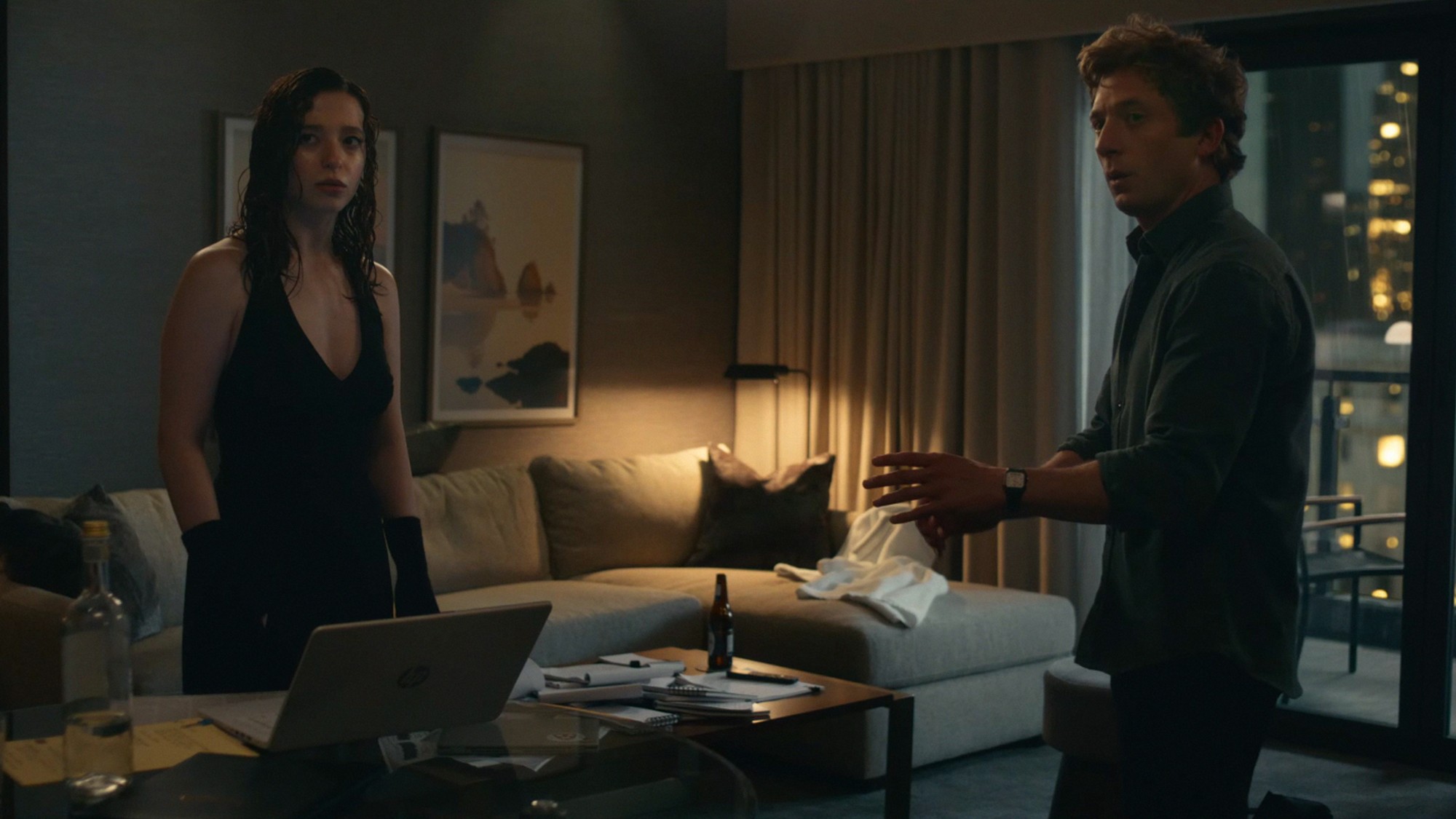 Dos personajes discuten junto a una laptop en una habitación de hotel en una escena de la película