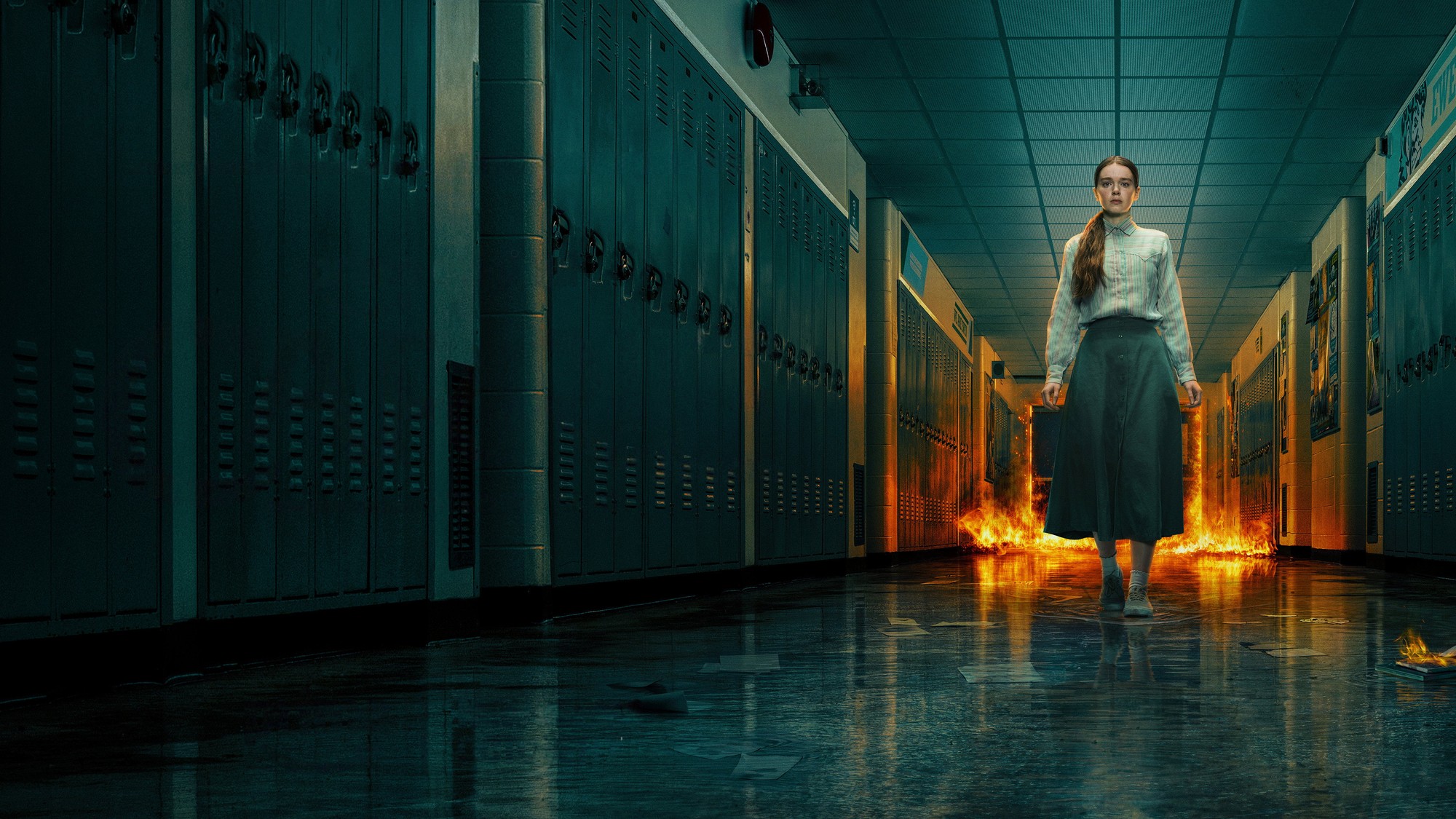 Carrie White camina por un pasillo de casilleros de la escuela mientras el fuego arde detrás de ella