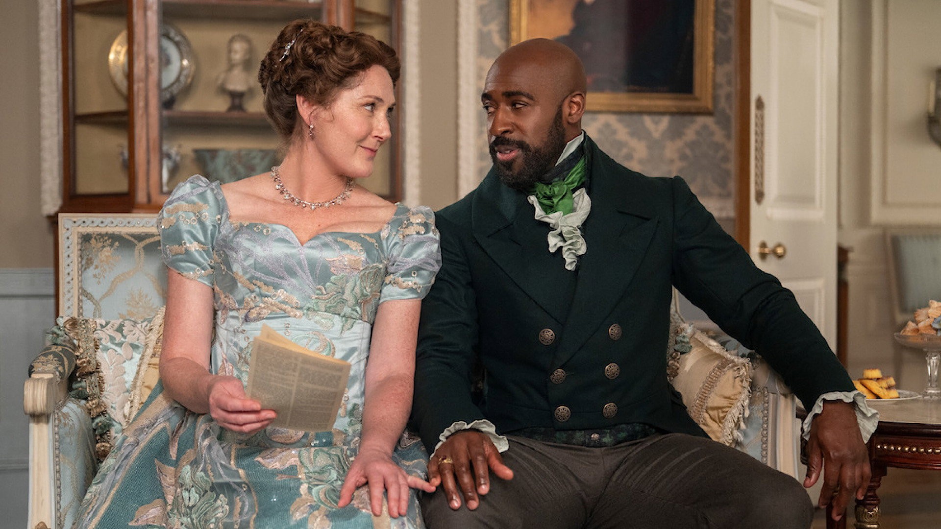 Ruth Gemmell como Lady Violet Bridgerton sentada en un sofá de un salón en la serie Los Bridgerton