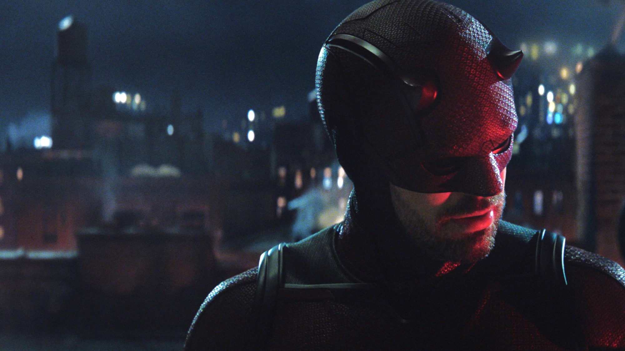 Charlie Cox como Daredevil con su traje rojo sobre una azotea de Nueva York de noche