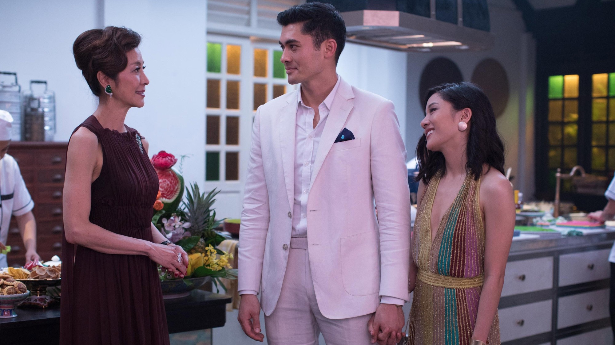 Michelle Yeoh, Henry Golding y Constance Wu conversan en una cocina en una escena de Locamente millonarios