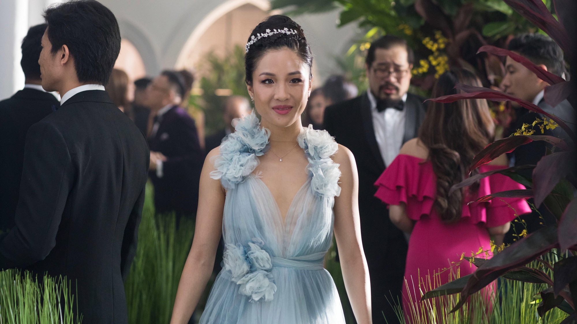 Constance Wu como Rachel Chu con vestido azul y tiara en una boda de lujo en Locamente millonarios