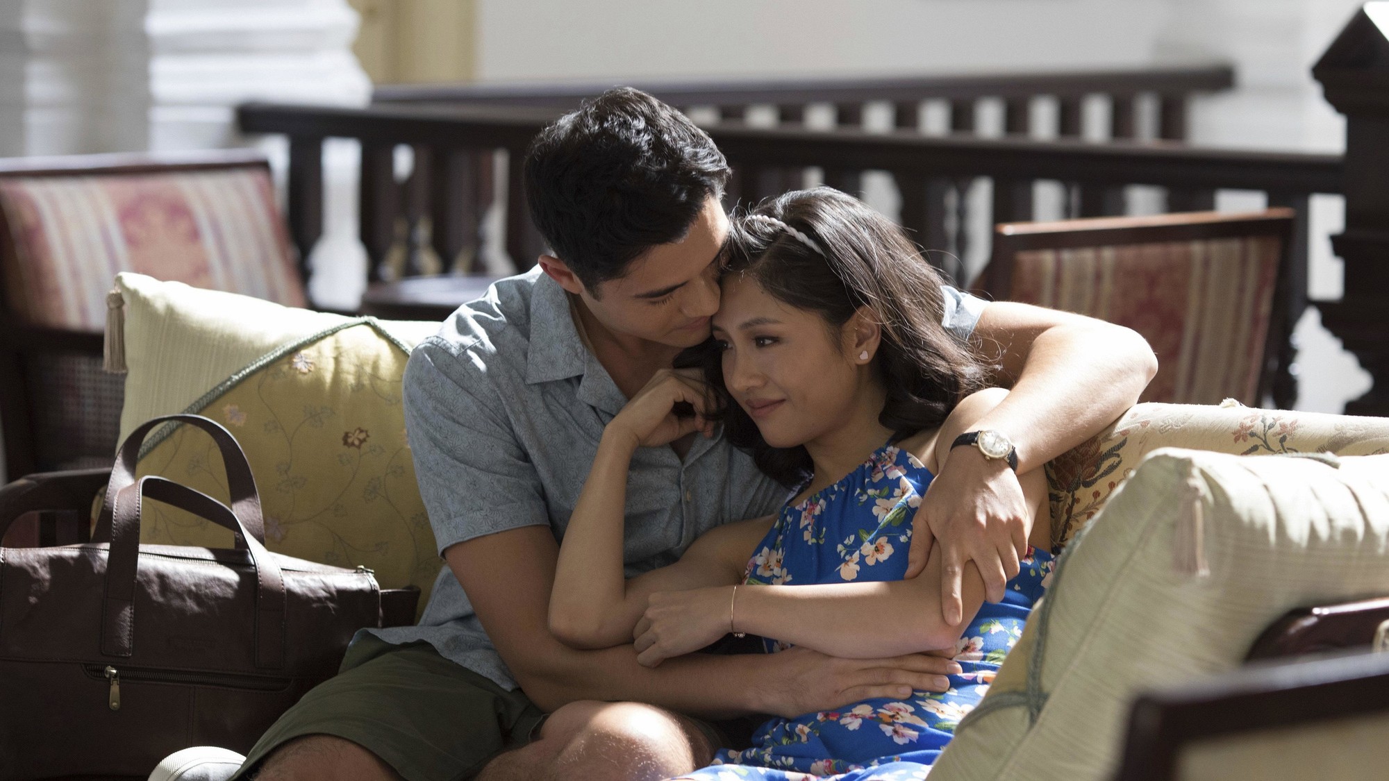Henry Golding abraza a Constance Wu en un sofá en una escena romántica de Locamente millonarios
