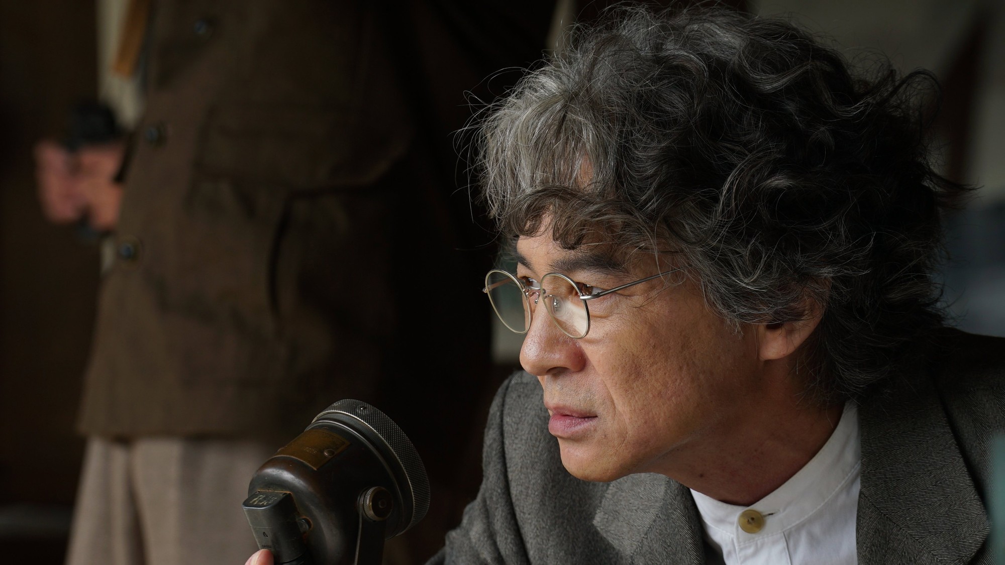 Un hombre de cabello canoso y anteojos redondos observa con atención en un despacho de la posguerra japonesa