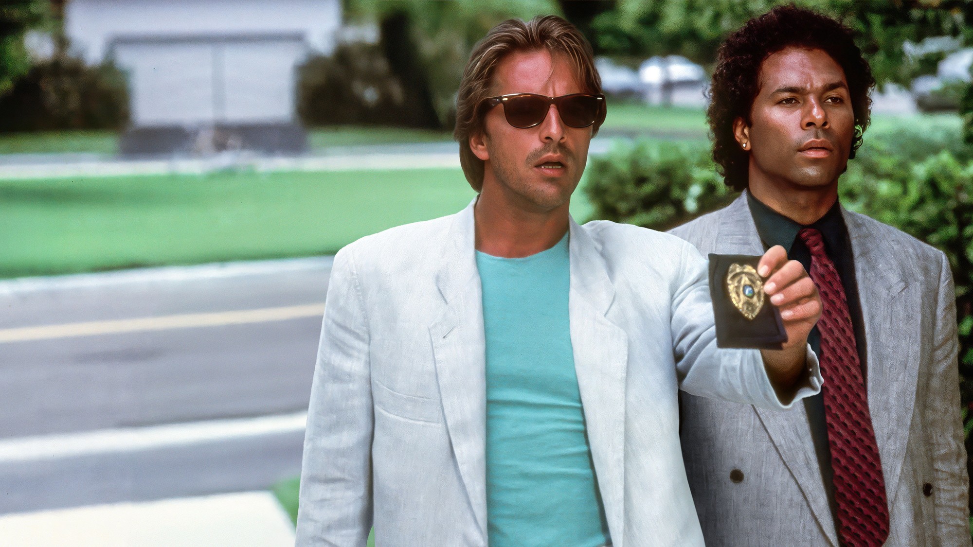 Don Johnson y Philip Michael Thomas como Crockett y Tubbs, mostrando una placa policial en la serie original Miami Vice