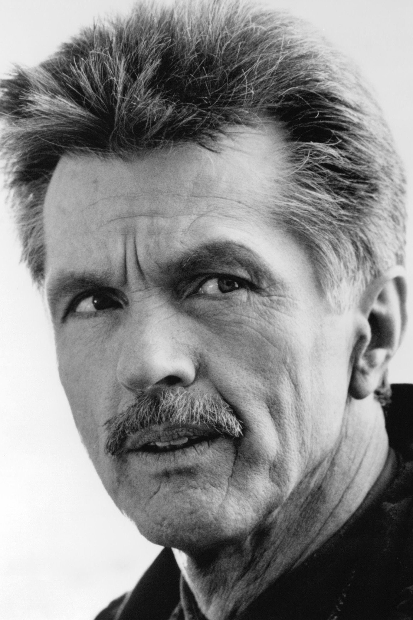 Retrato en blanco y negro de Tom Skerritt en su madurez, con bigote y el cabello peinado hacia atrás