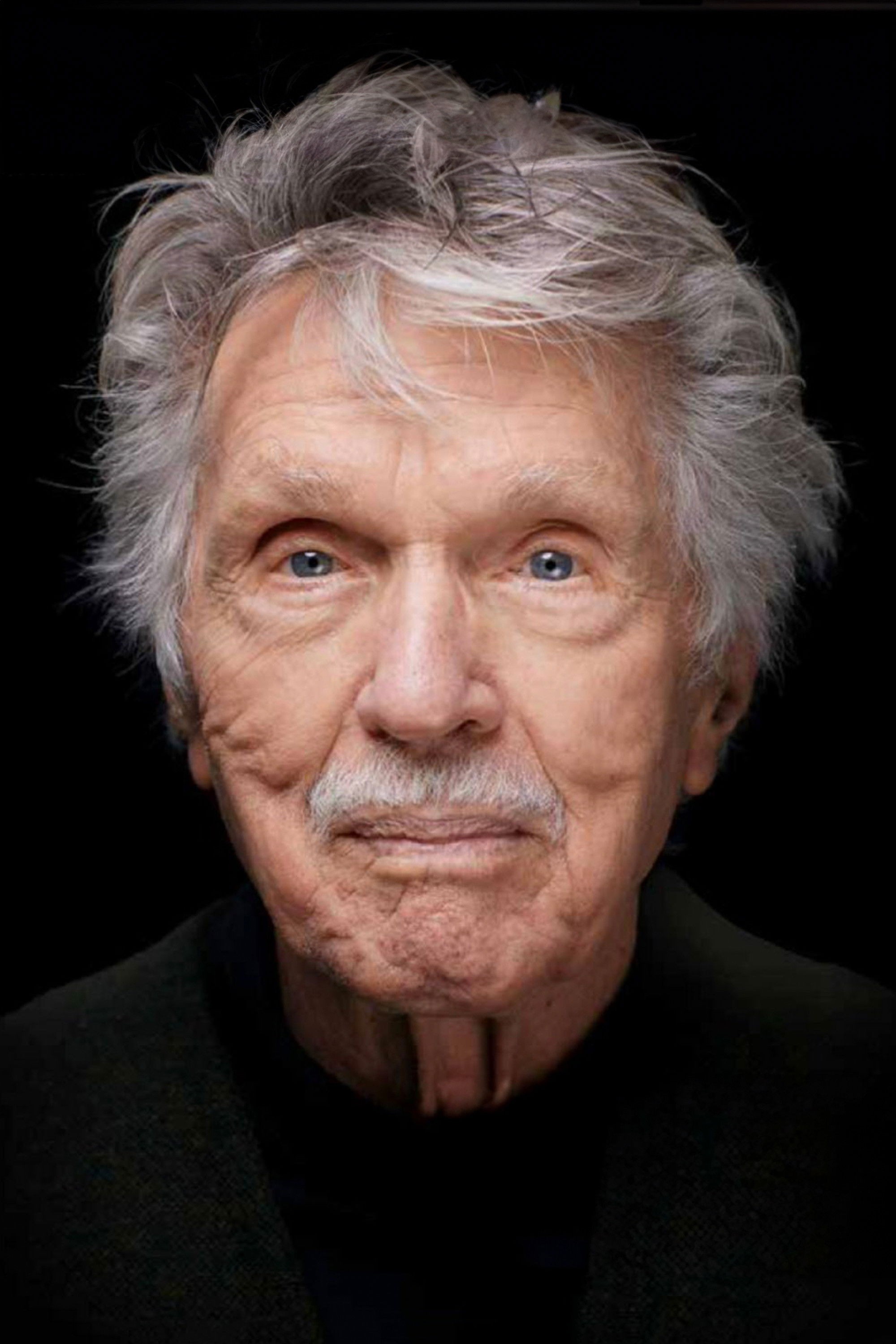Retrato reciente de Tom Skerritt, con el cabello canoso y bigote blanco, sobre un fondo negro