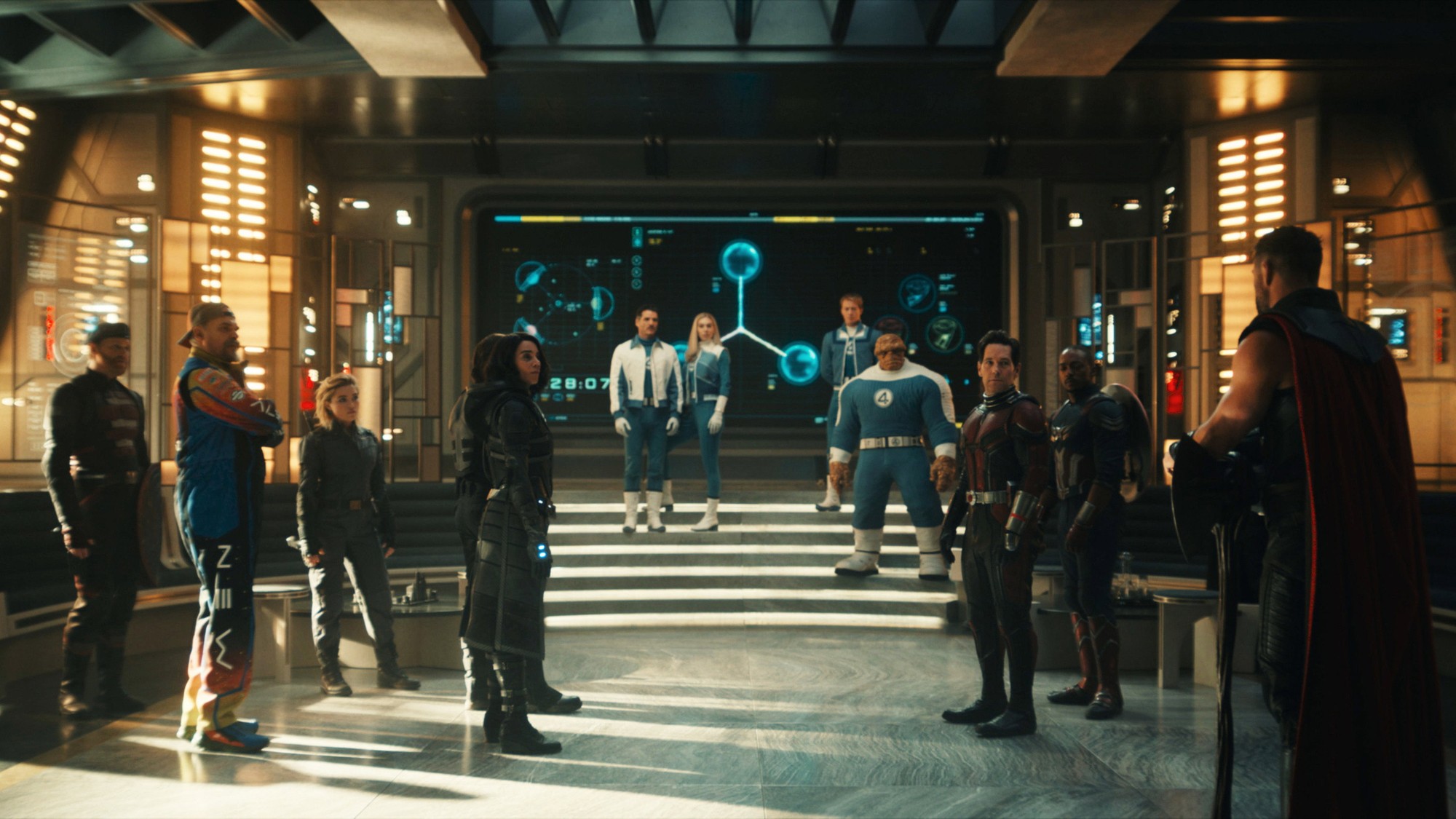 Los Vengadores y los Cuatro Fantásticos reunidos en el gran salón de la Torre de los Vengadores frente a una pantalla holográfica