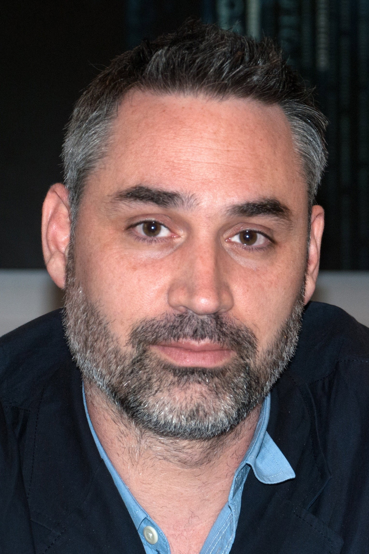 Retrato del director y guionista británico Alex Garland con barba canosa y camisa azul