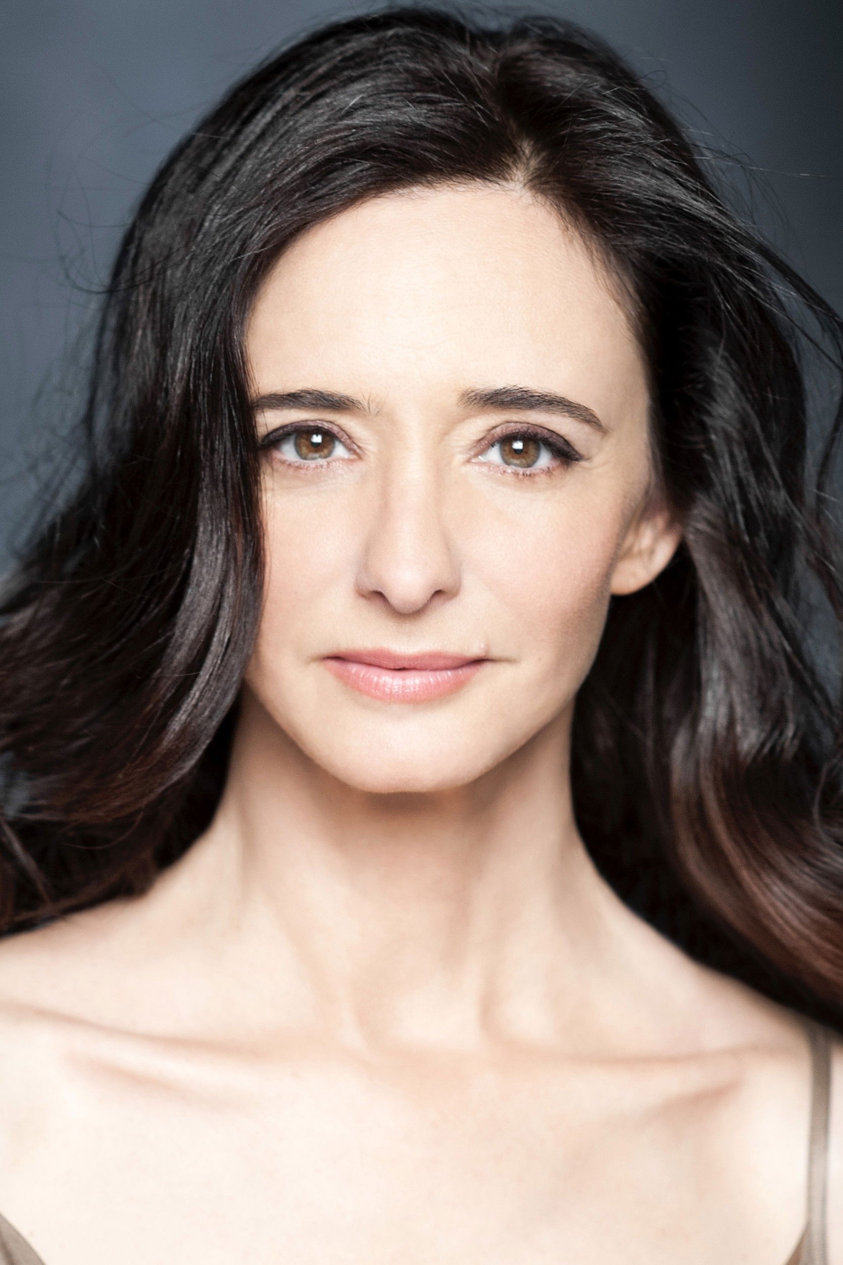 Retrato de Ana Torrent, doña Paula en La Regenta, con el cabello oscuro y largo sobre un fondo azul oscuro