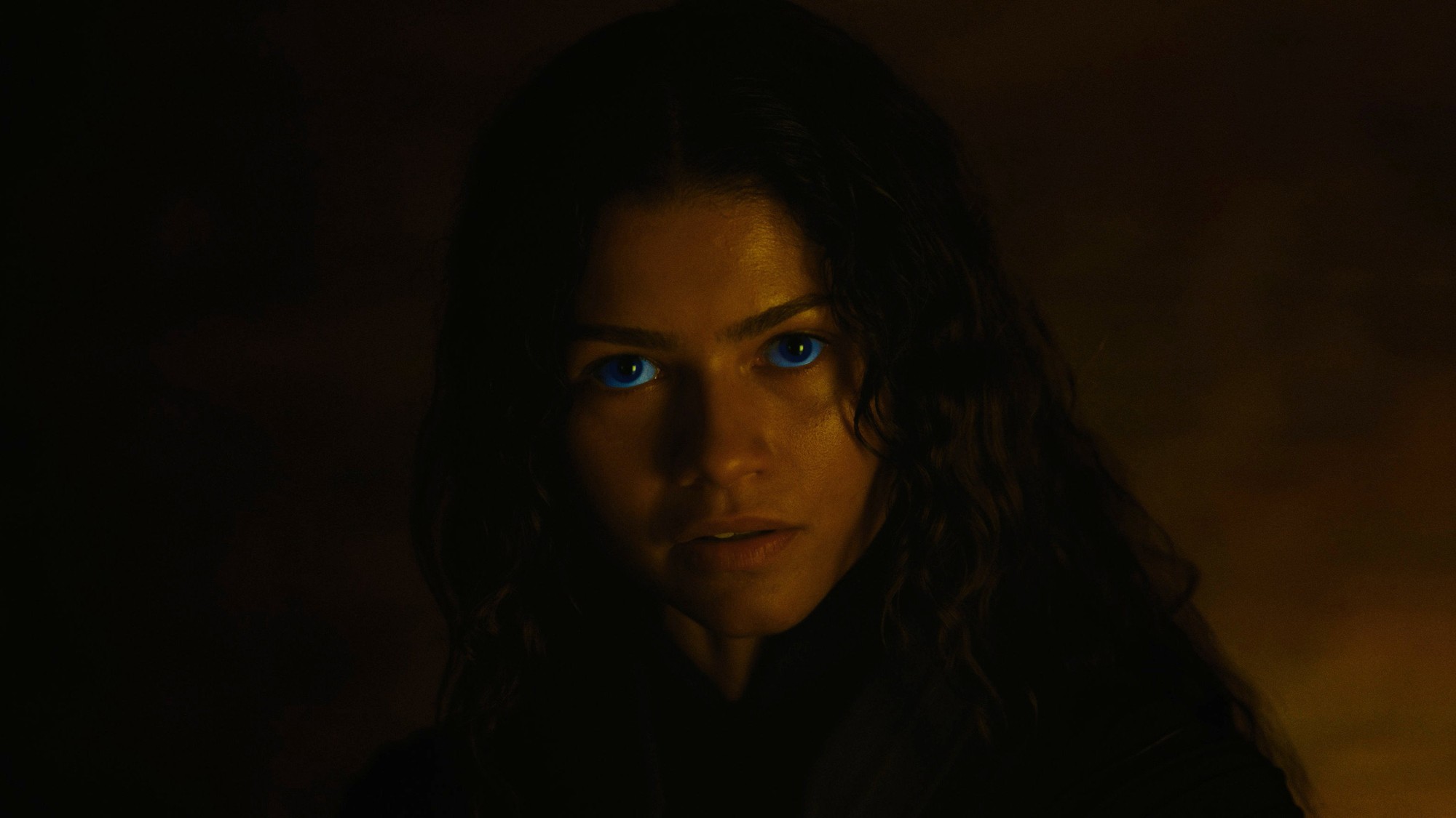 Primer plano de Zendaya como Chani con los ojos azules de los fremen iluminados en la penumbra