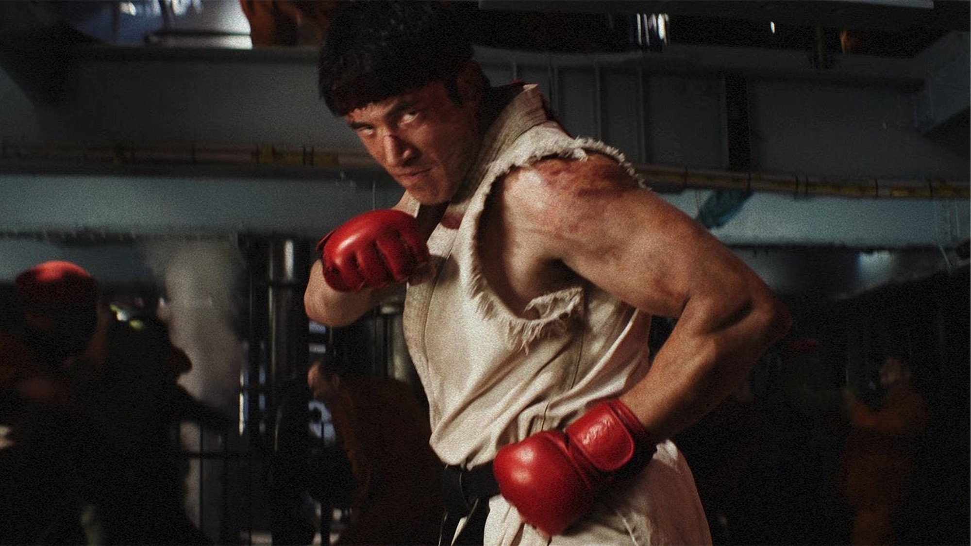 Ryu, con su clásico uniforme blanco y guantes rojos, en guardia de combate en un gimnasio en Street Fighter