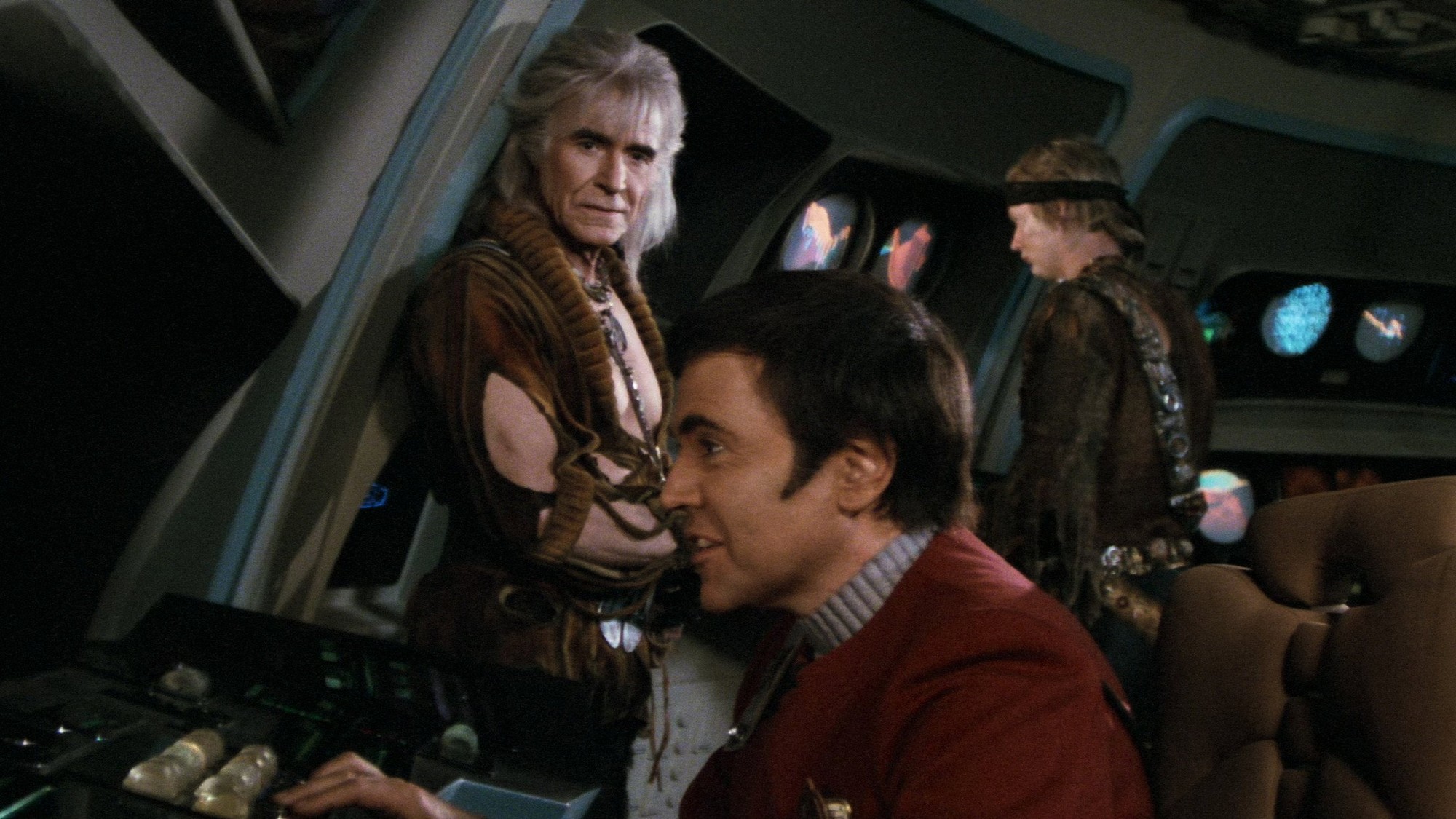 Chekov, interpretado por Walter Koenig, sentado ante una consola mientras Khan lo observa de pie a sus espaldas en Star Trek II: The Wrath of Khan