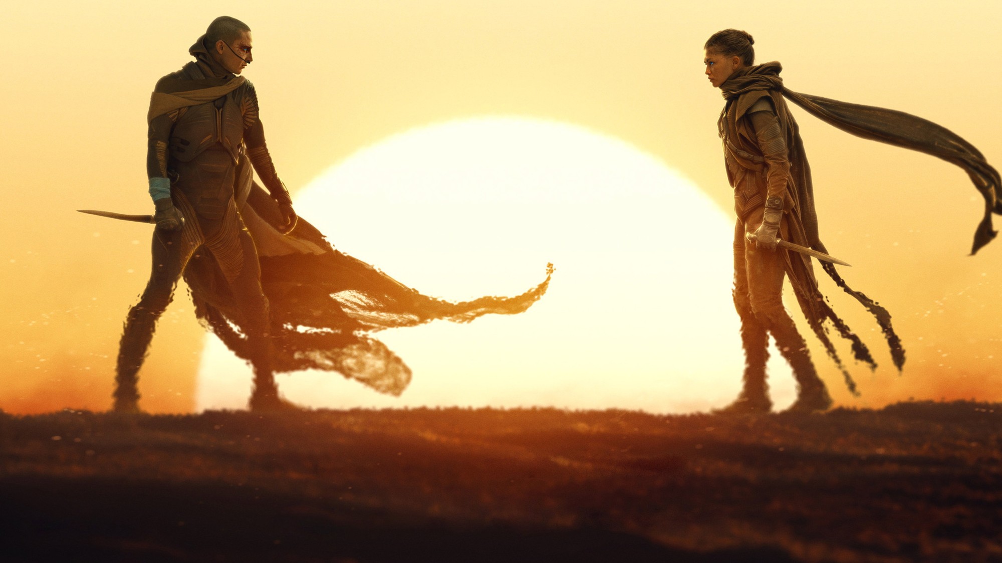 Paul Atreides y Chani se enfrentan con cuchillos en la mano frente a un enorme sol del desierto en Dune: Parte Tres