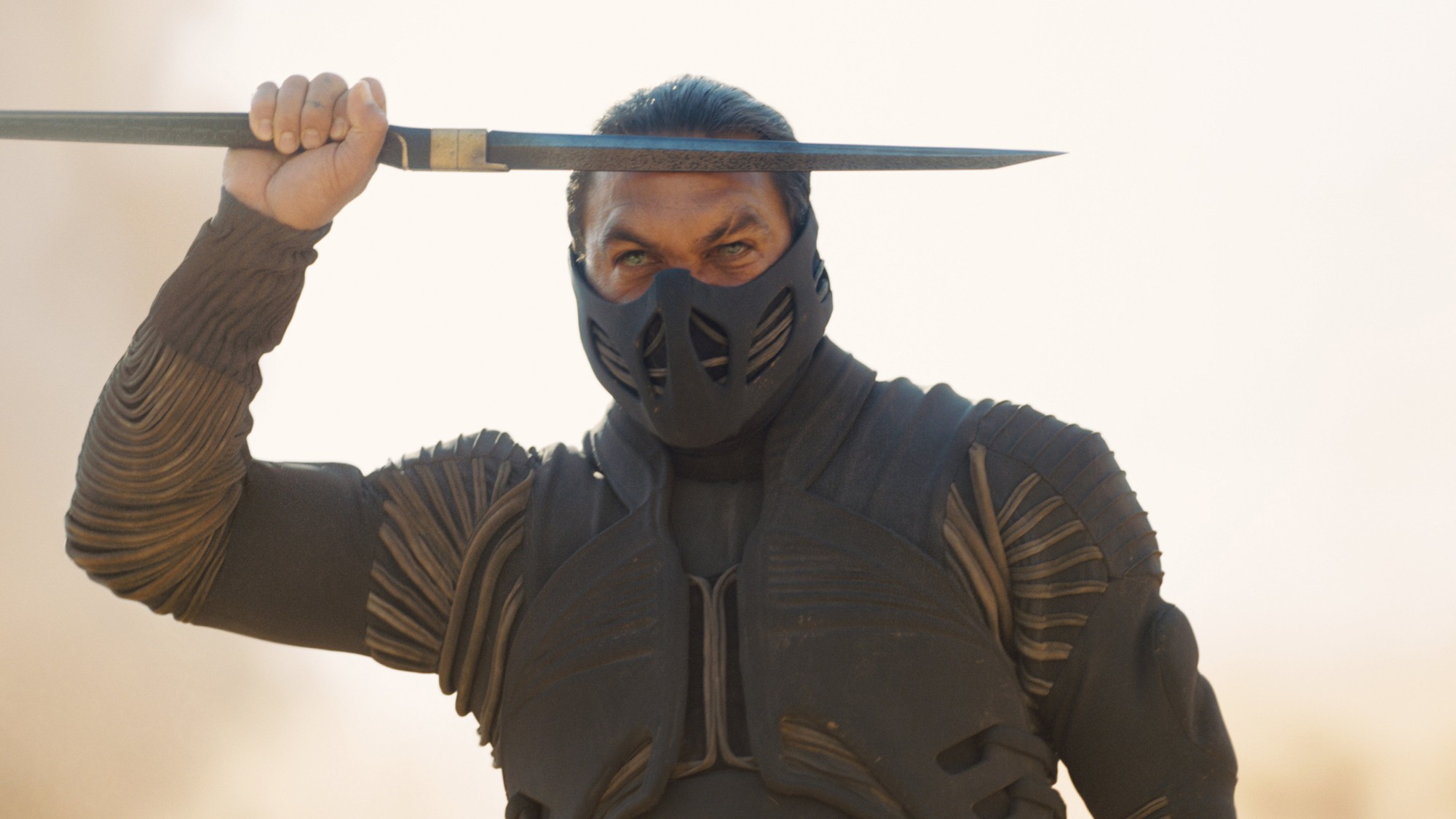 Jason Momoa con máscara negra y traje de combate levanta una espada sobre su cabeza en Dune: Parte Tres
