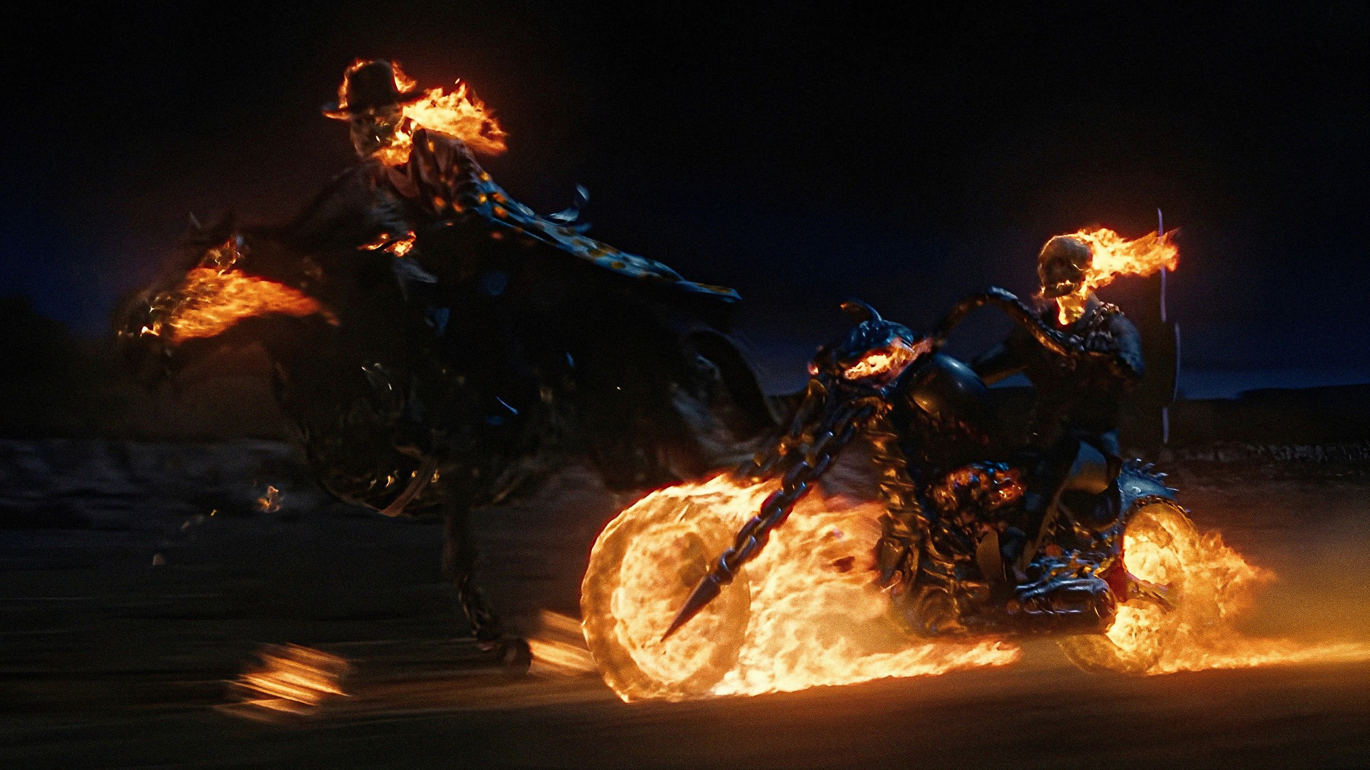 Dos jinetes con el cráneo en llamas cabalgan de noche, uno a caballo y otro en una motocicleta envuelta en fuego, en Ghost Rider de 2007