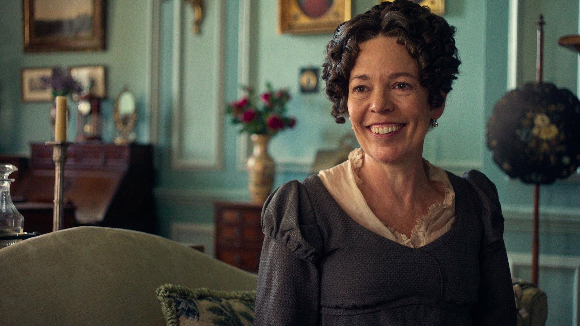 Olivia Colman sonríe como la señora Bennet en un salón de paredes verde agua