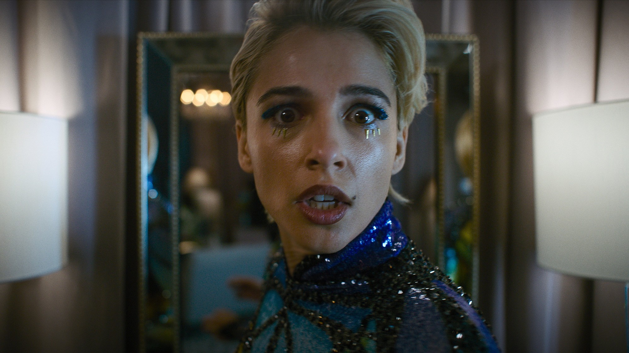 Naomi Scott como la estrella pop Skye Riley, con los ojos muy abiertos y gesto de pánico frente a un espejo, en Smile 2